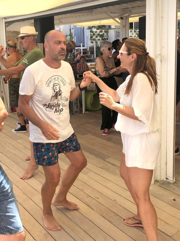 Maglietta Lindy Hop by Spirit of St. Louis indossata da un cliente durante il Summer Jamboree 2022 mentre balla in un locale sulla spiaggia